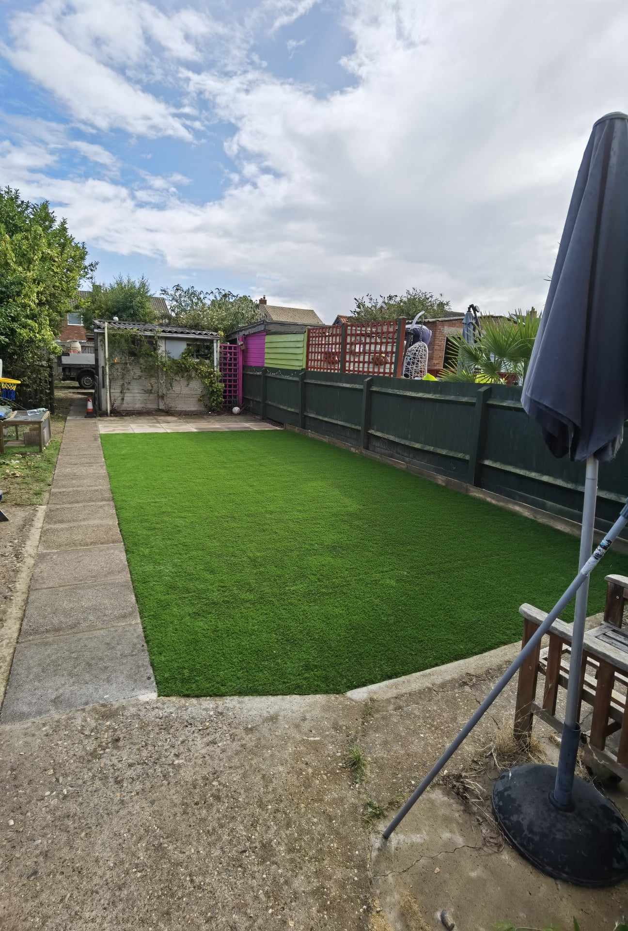 Artificial grass installation Suffolk — Bright green synthetic turf lawn in residential garden space