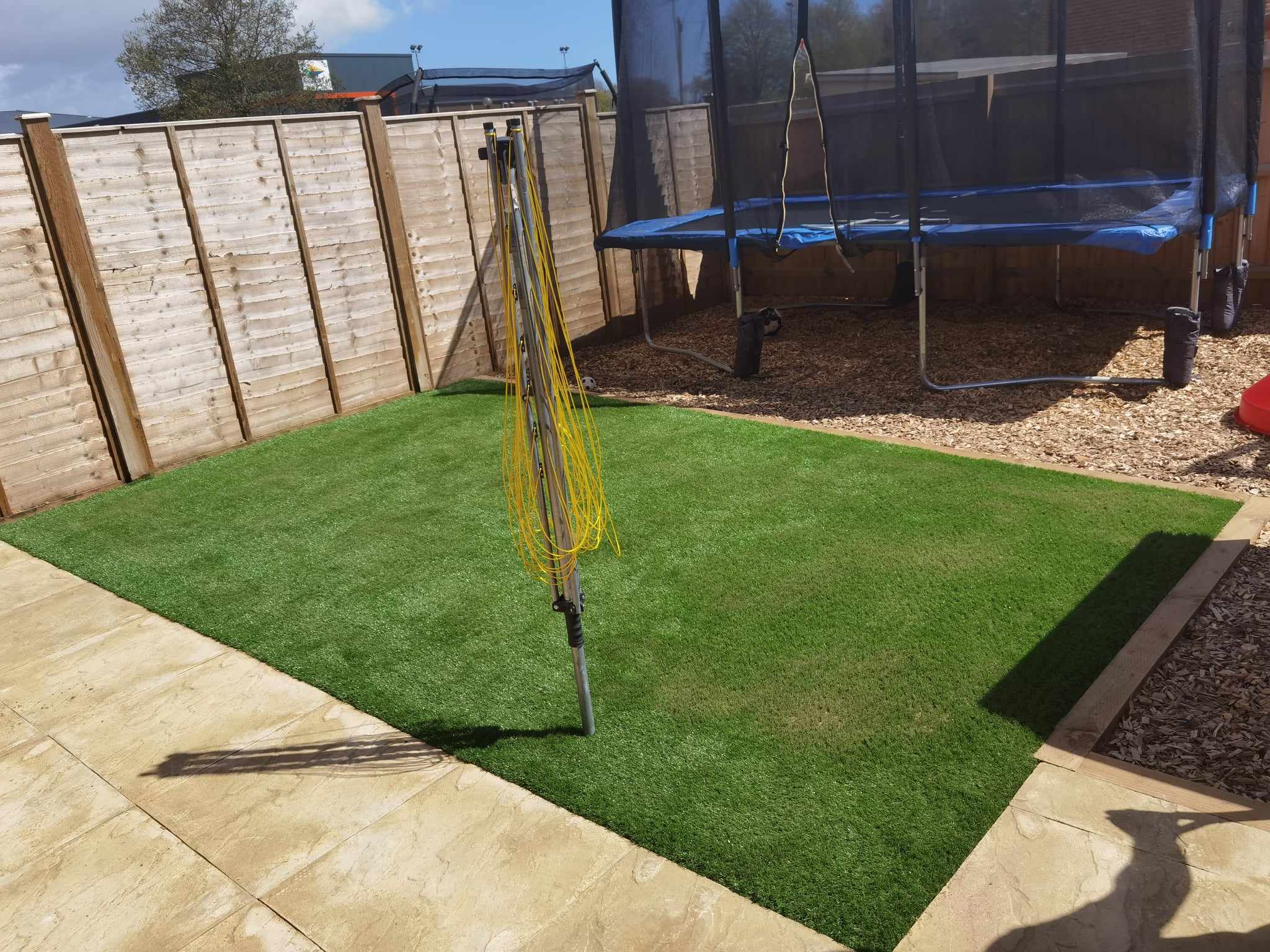 Artificial grass installation Suffolk — Vibrant green artificial turf installation with patio edging and trampoline