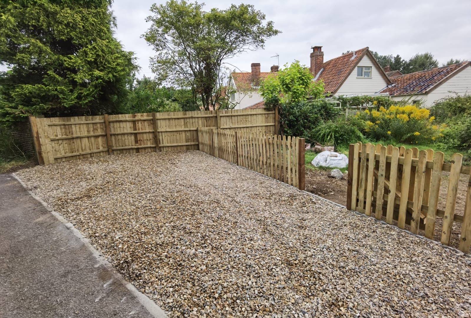 Driveway installation Suffolk — Gravel driveway with wooden fencing and garden beyond