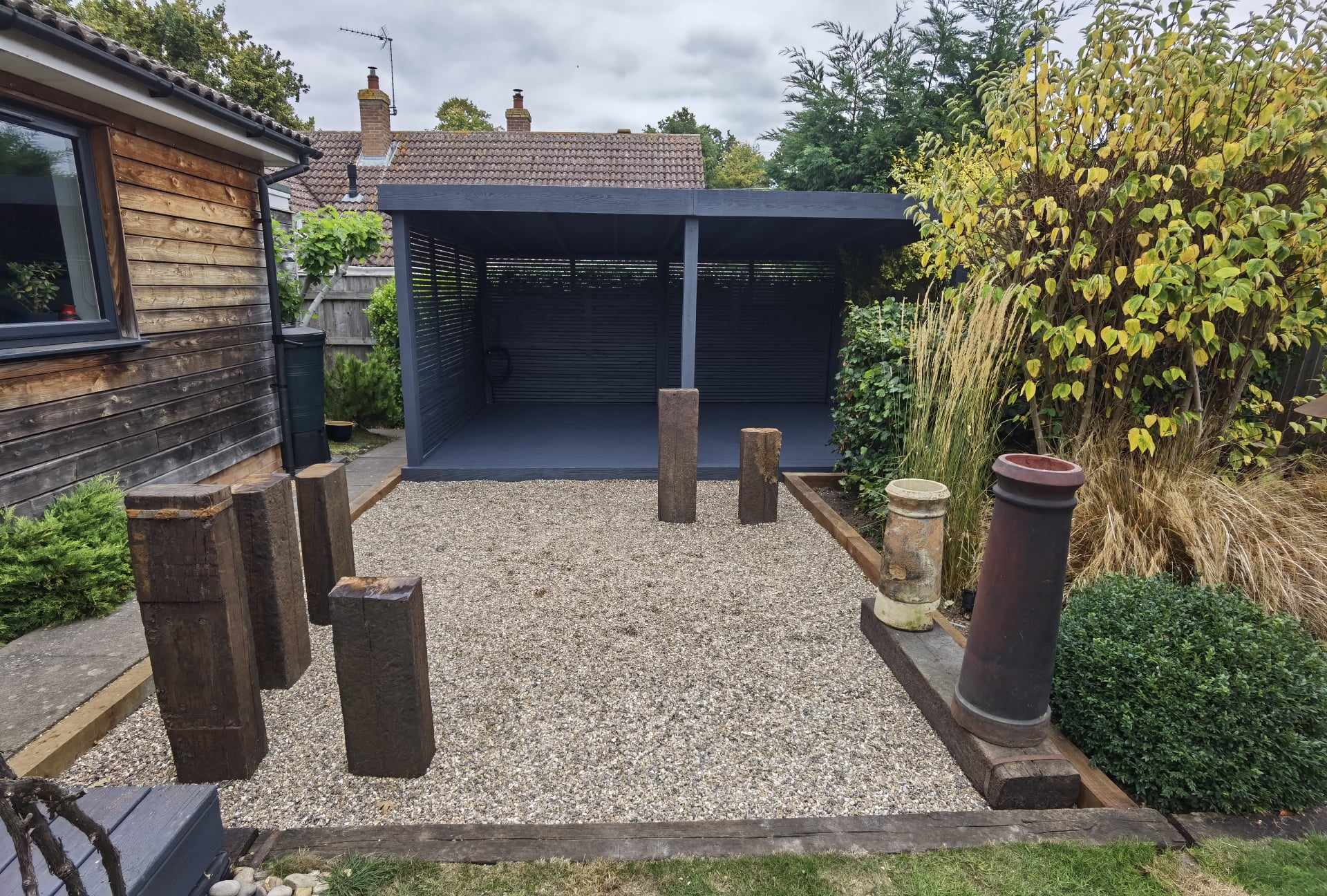 Driveway installation Suffolk — Gravel driveway with timber bollards leading to modern garage