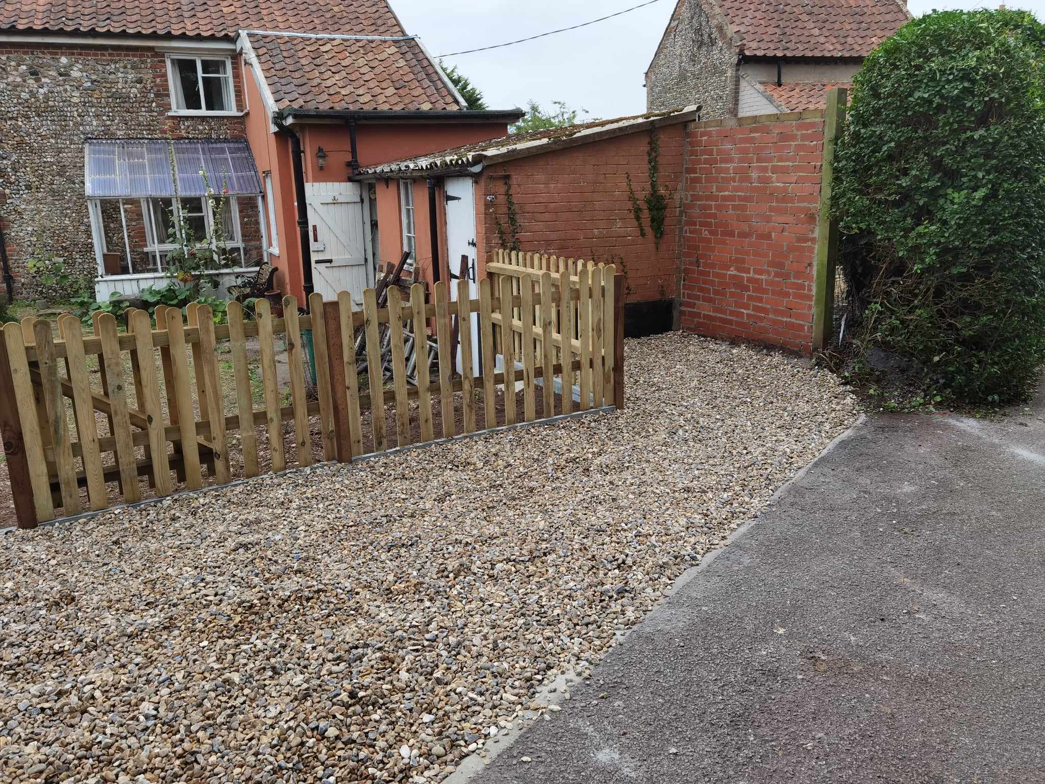 Driveway installation Suffolk — Gravel driveway with wooden picket gate entrance to residential property