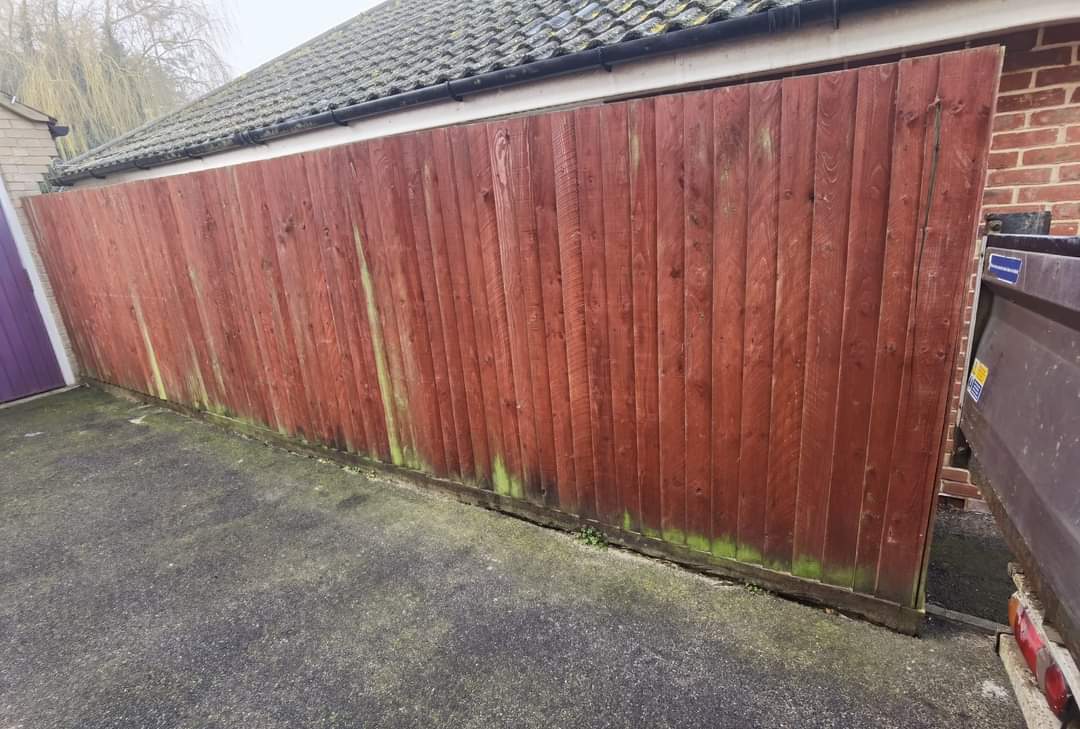 Fencing & gates Suffolk — Red wooden fence with moss growth, showing weathering and age