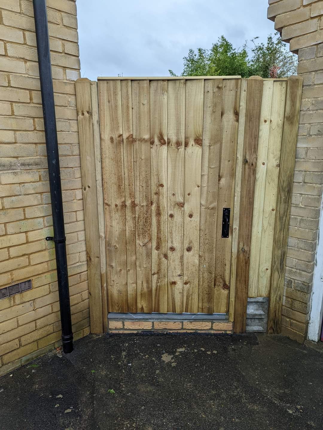 Fencing & gates Suffolk — Wooden fence gate with weathered finish between brick walls
