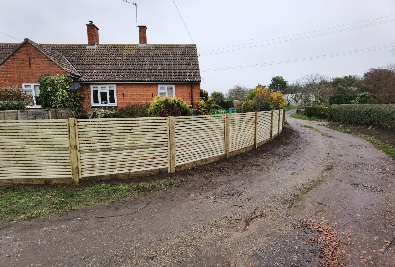 Fencing & gates Suffolk — New horizontal timber fence panels along rural driveway entrance