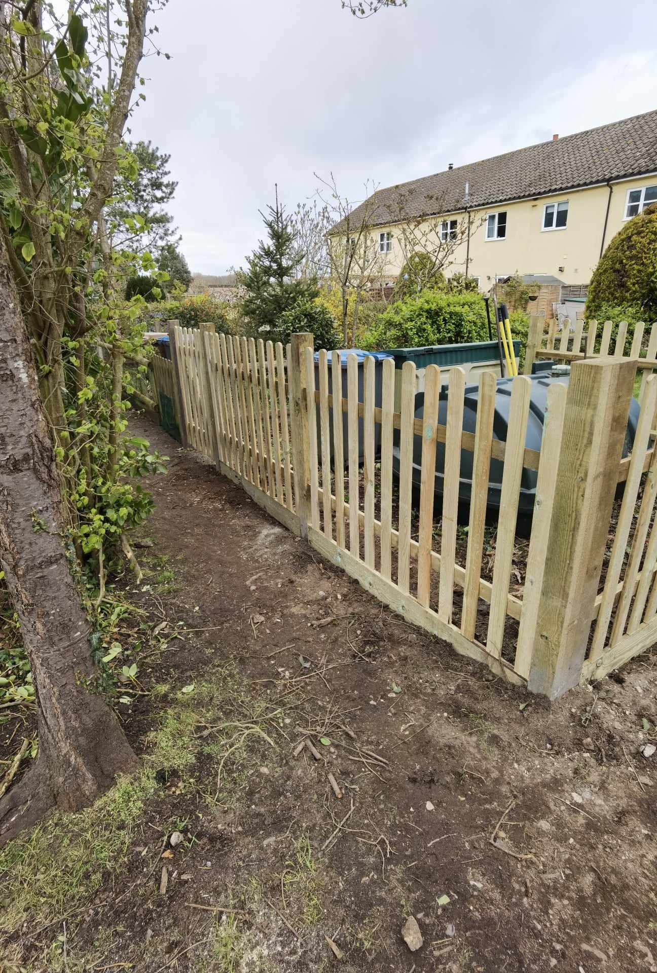 Fencing & gates Suffolk — Wooden picket fence enclosing residential garden area with parked cars