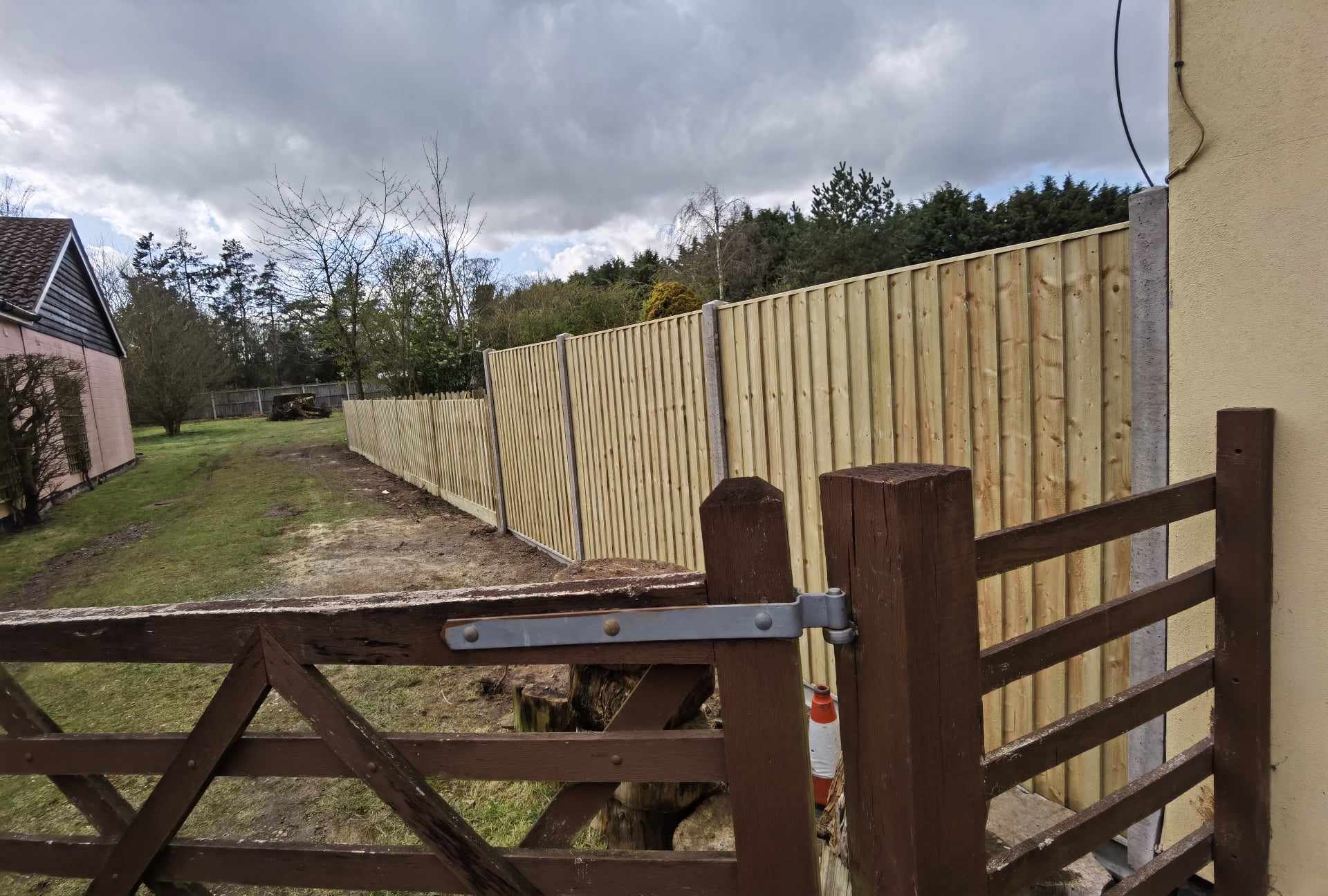 Fencing & gates Suffolk — Wooden and corrugated metal fencing with gates in rural property setting.