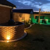 Garden lighting Suffolk — Evening garden with prominent accent lighting on landscaping features