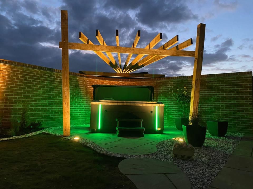 Garden lighting Suffolk — Illuminated patio space with green ambient lighting and wooden pergola structure