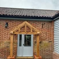 Garden landscaping project Suffolk — Brick cottage entrance with white door and pitched roof porch