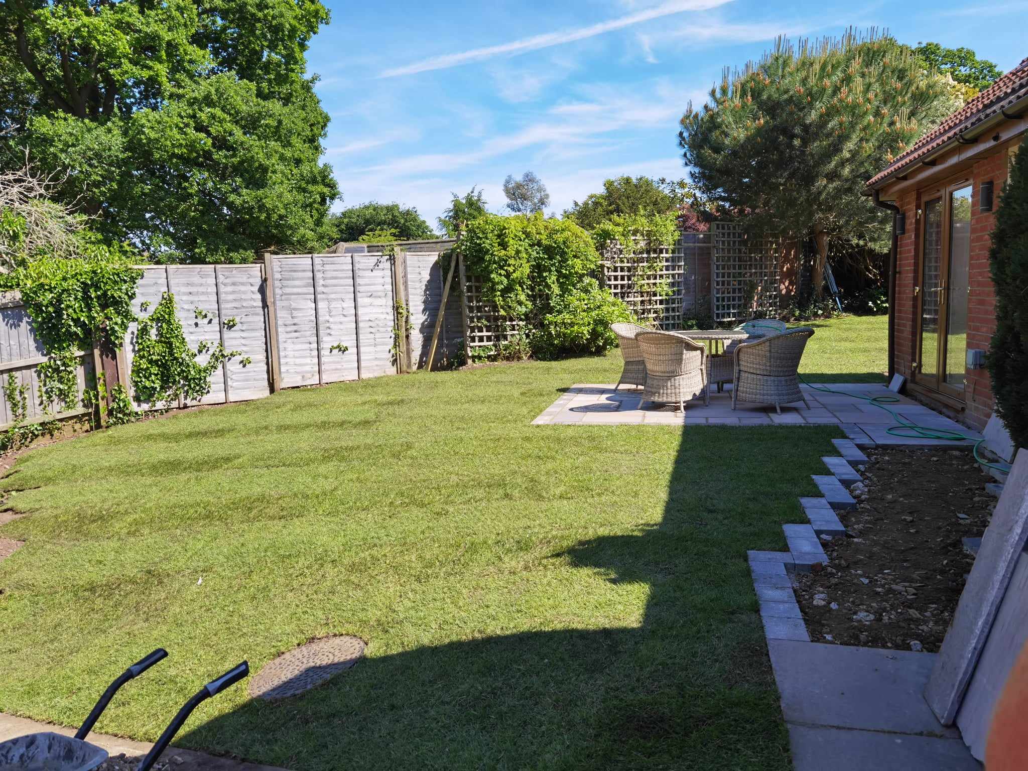 Garden landscaping project Suffolk — Wide garden overview showing lawn, patio, fencing, and landscaped borders