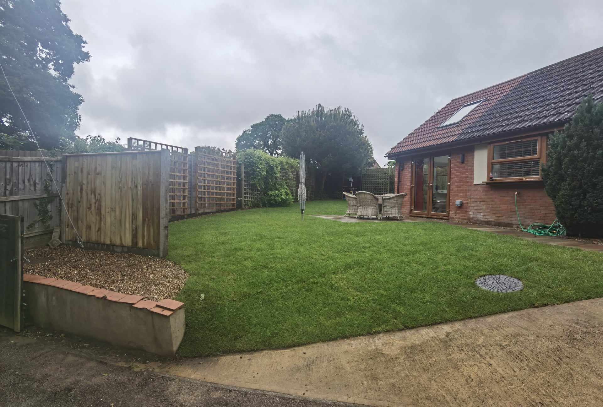Garden landscaping project Suffolk — Wide shot of finished residential garden with turf, fencing, and brick house