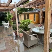Patio installation Suffolk — Stone slab paved courtyard with pergola, seating, and potted plants