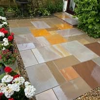 Patio installation Suffolk — Multi-colored stone slabs forming decorative patio with flower bed borders