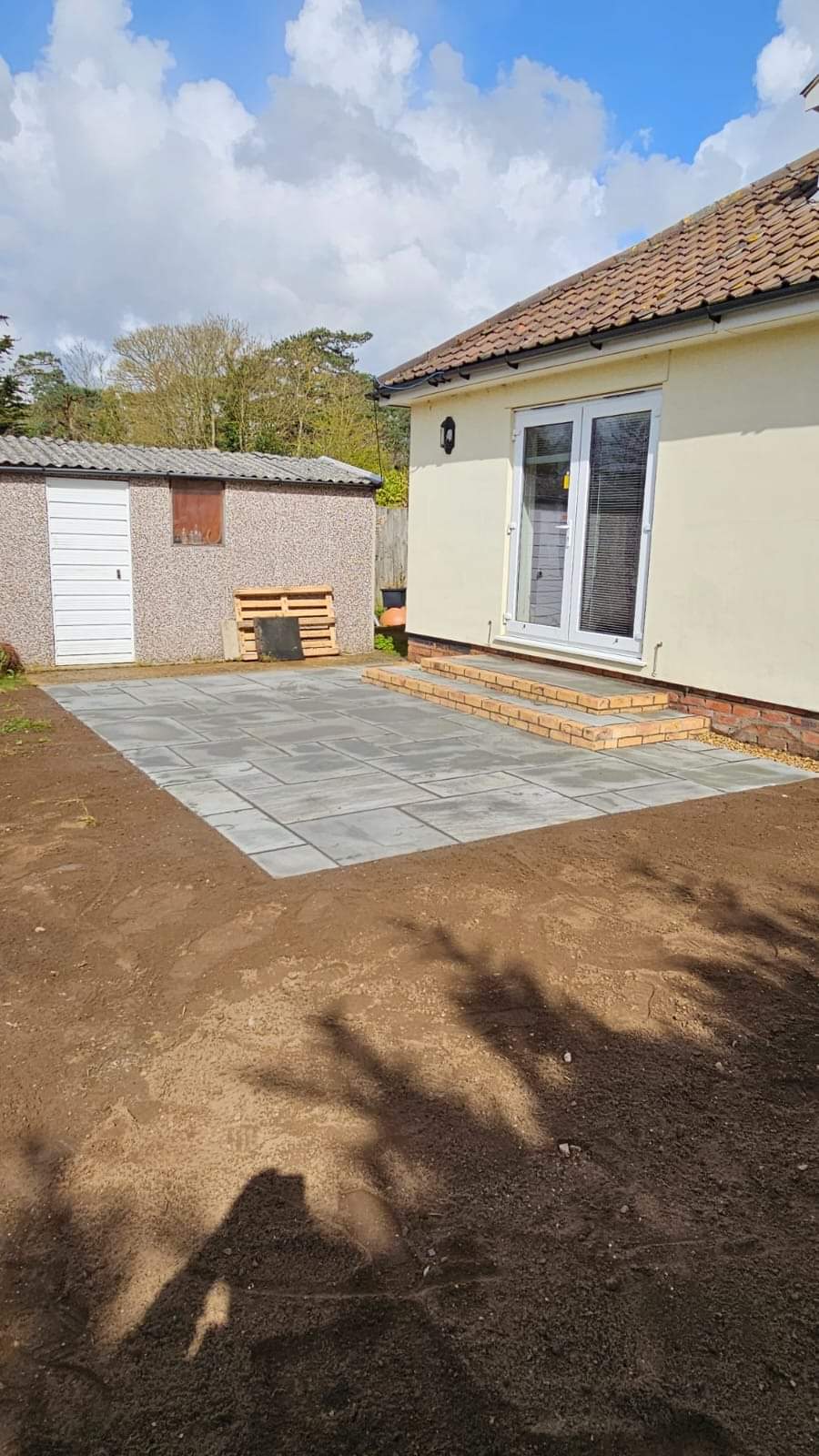 Patio installation Suffolk — Newly installed grey stone slab patio with brick border edging