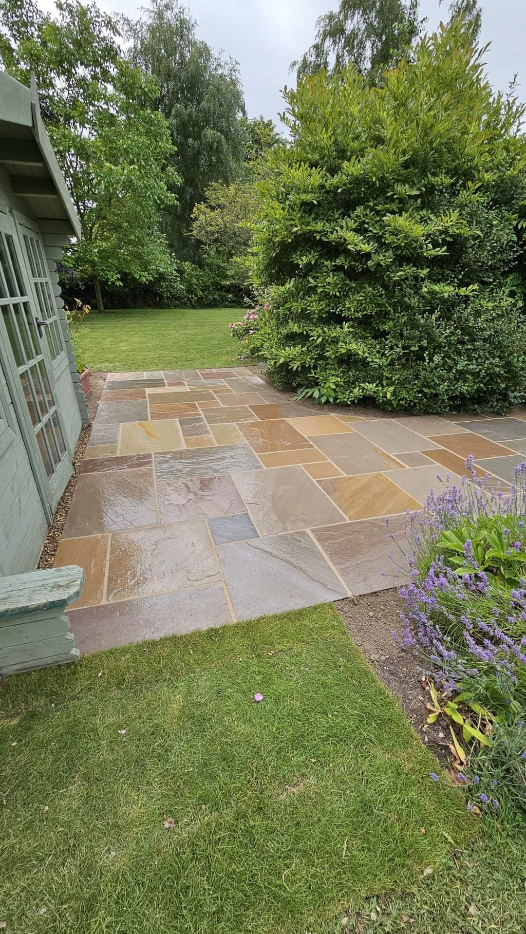 Patio installation Suffolk — Indian sandstone patio with geometric pattern layout, wet surface visible