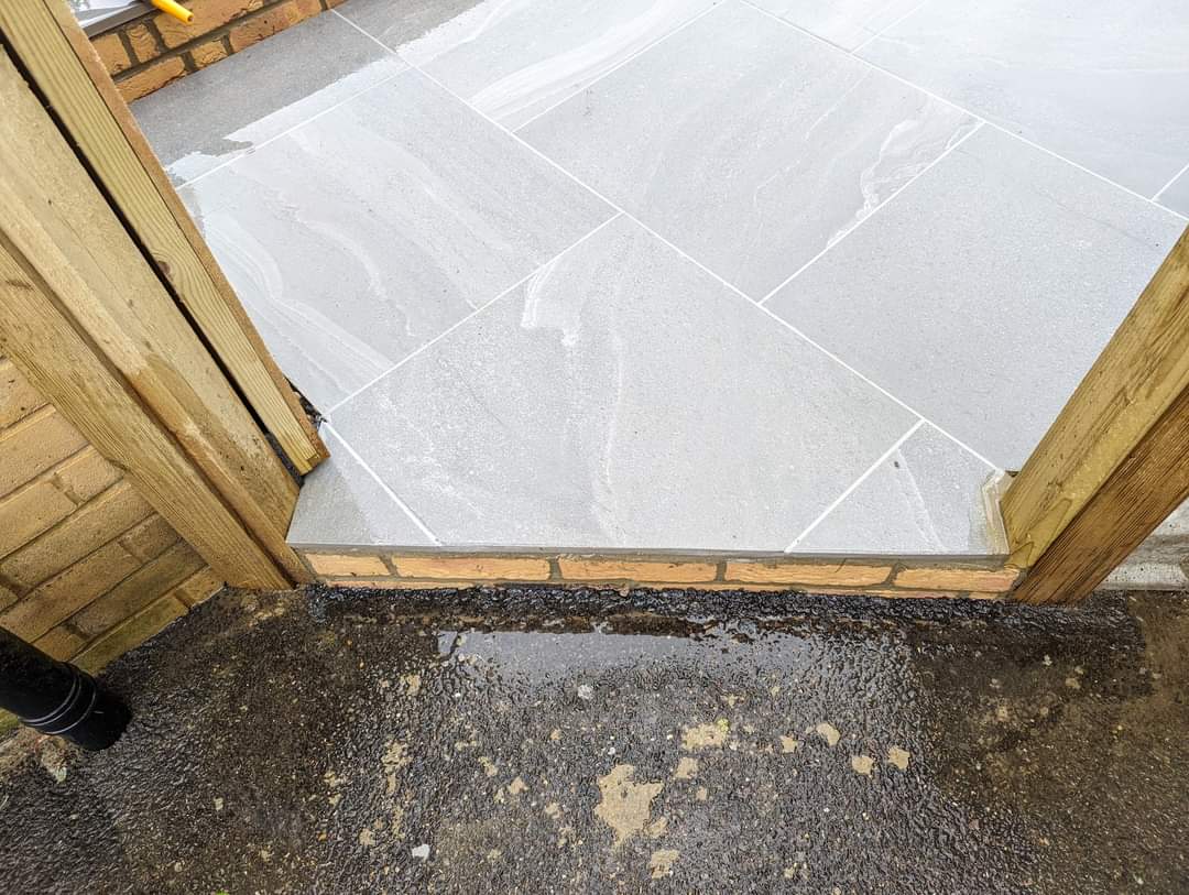 Patio installation Suffolk — Large grey stone slabs being laid during installation process