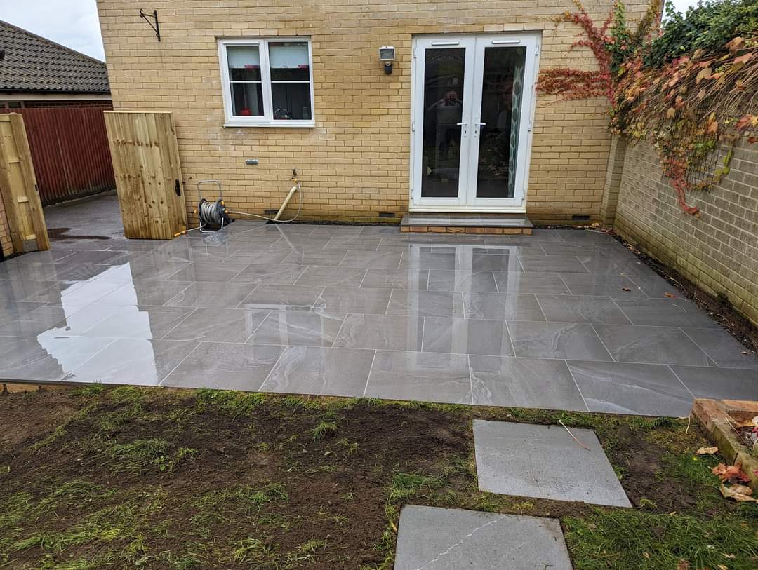 Patio installation Suffolk — Newly laid grey porcelain slab patio with wet reflective surface