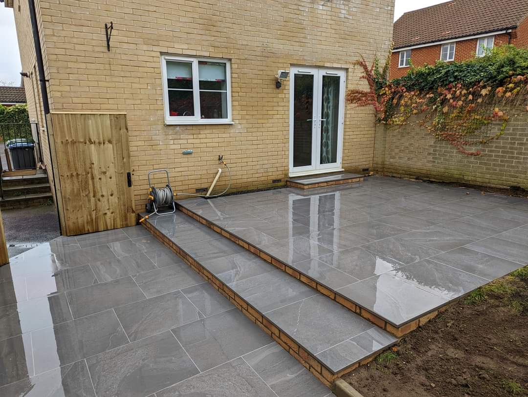 Patio installation Suffolk — Large slate paved patio with brick border, freshly laid and wet