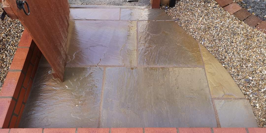 Patio installation Suffolk — Wet Indian sandstone patio with visible slab joints and gravel borders