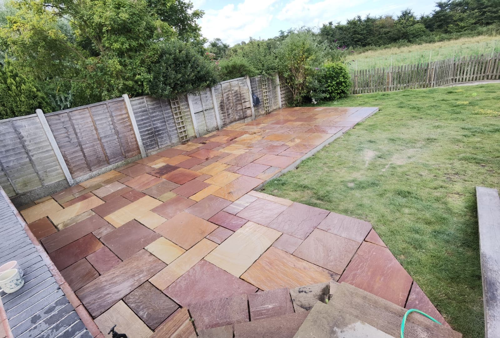 Patio installation Suffolk — Indian sandstone patio with herringbone pattern layout in warm tones