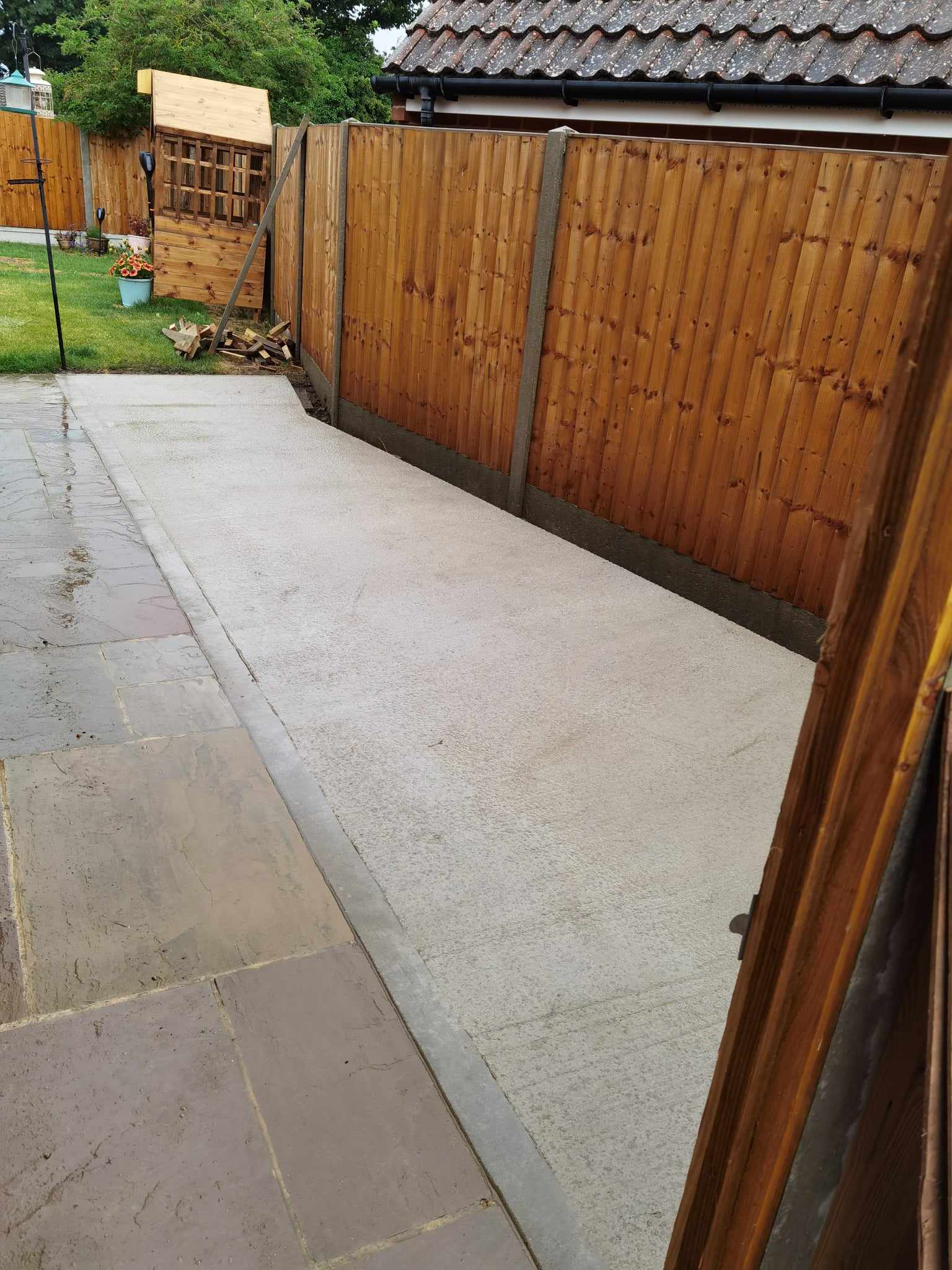 Patio installation Suffolk — Stone slab paved pathway area with wooden fence bordering