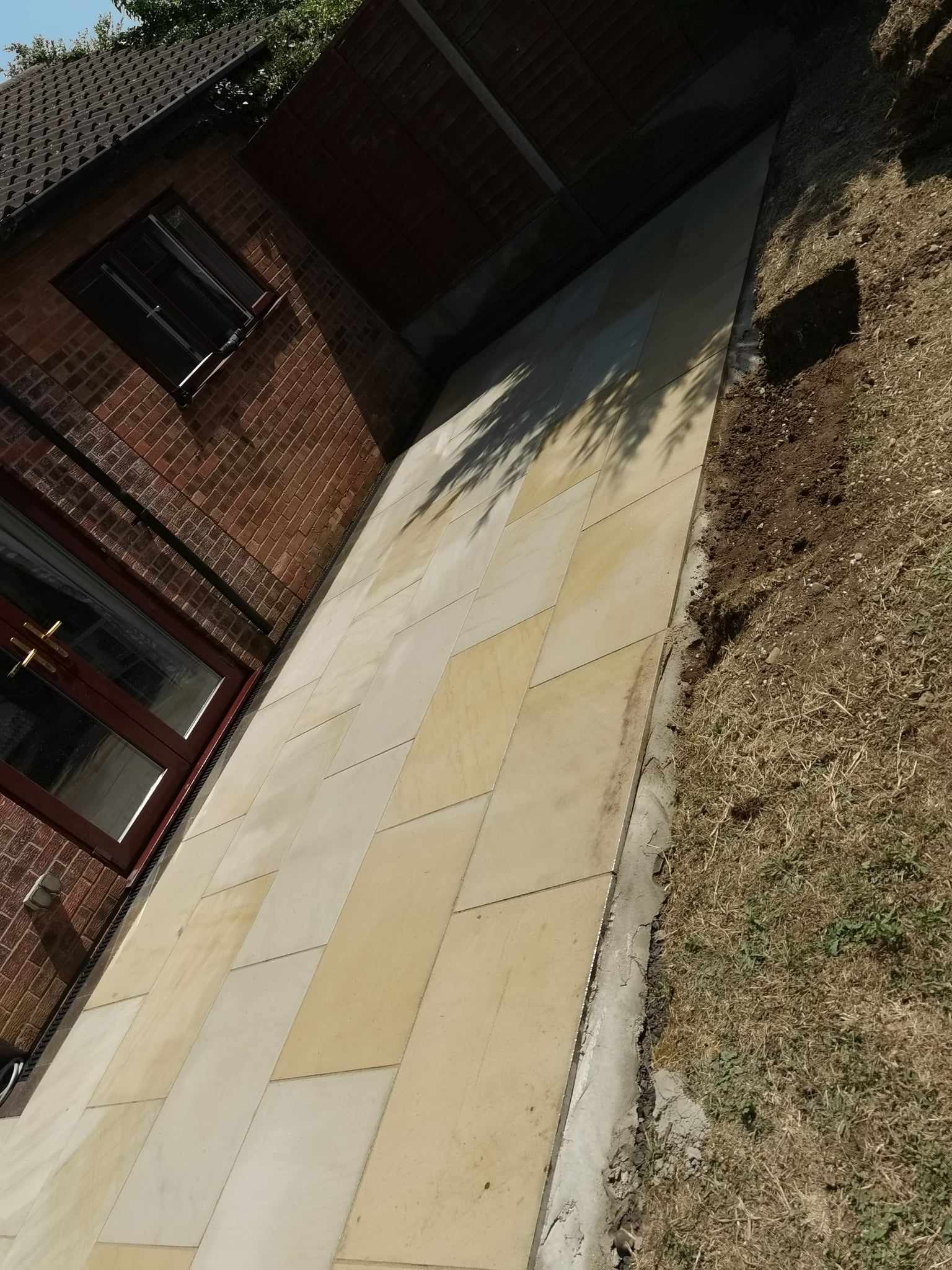 Patio installation Suffolk — Cream and beige sandstone paving slabs with herringbone pattern layout