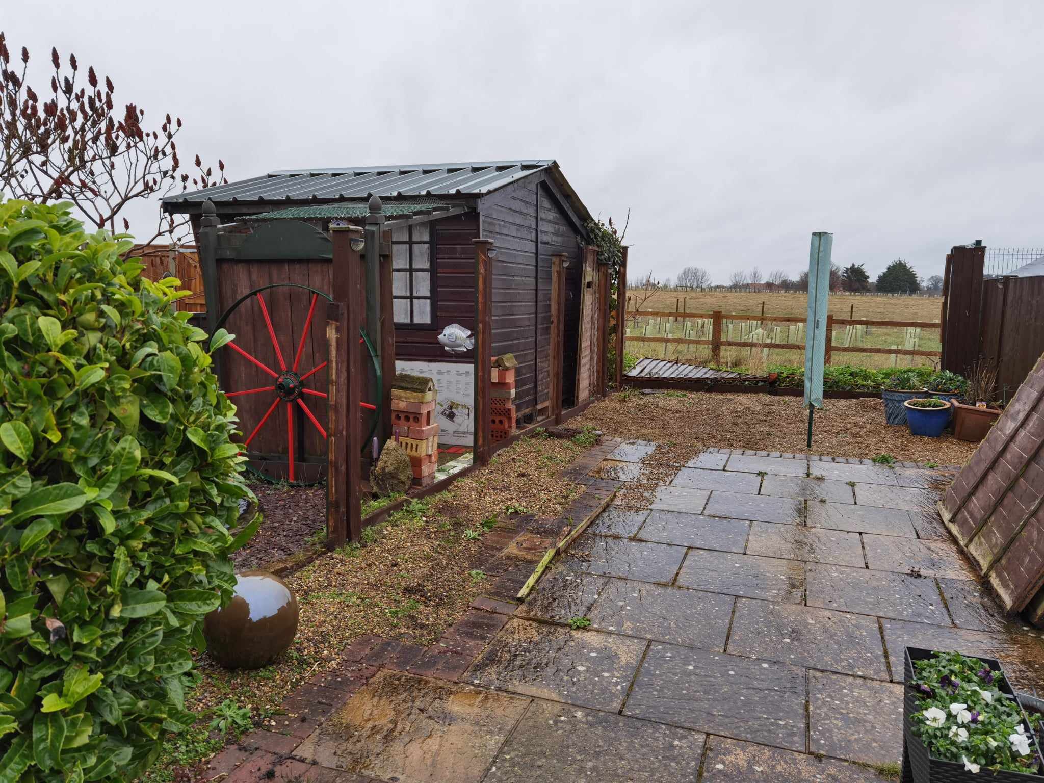 Patio installation Suffolk — Stone slab paved garden seating area with rustic shed and fencing