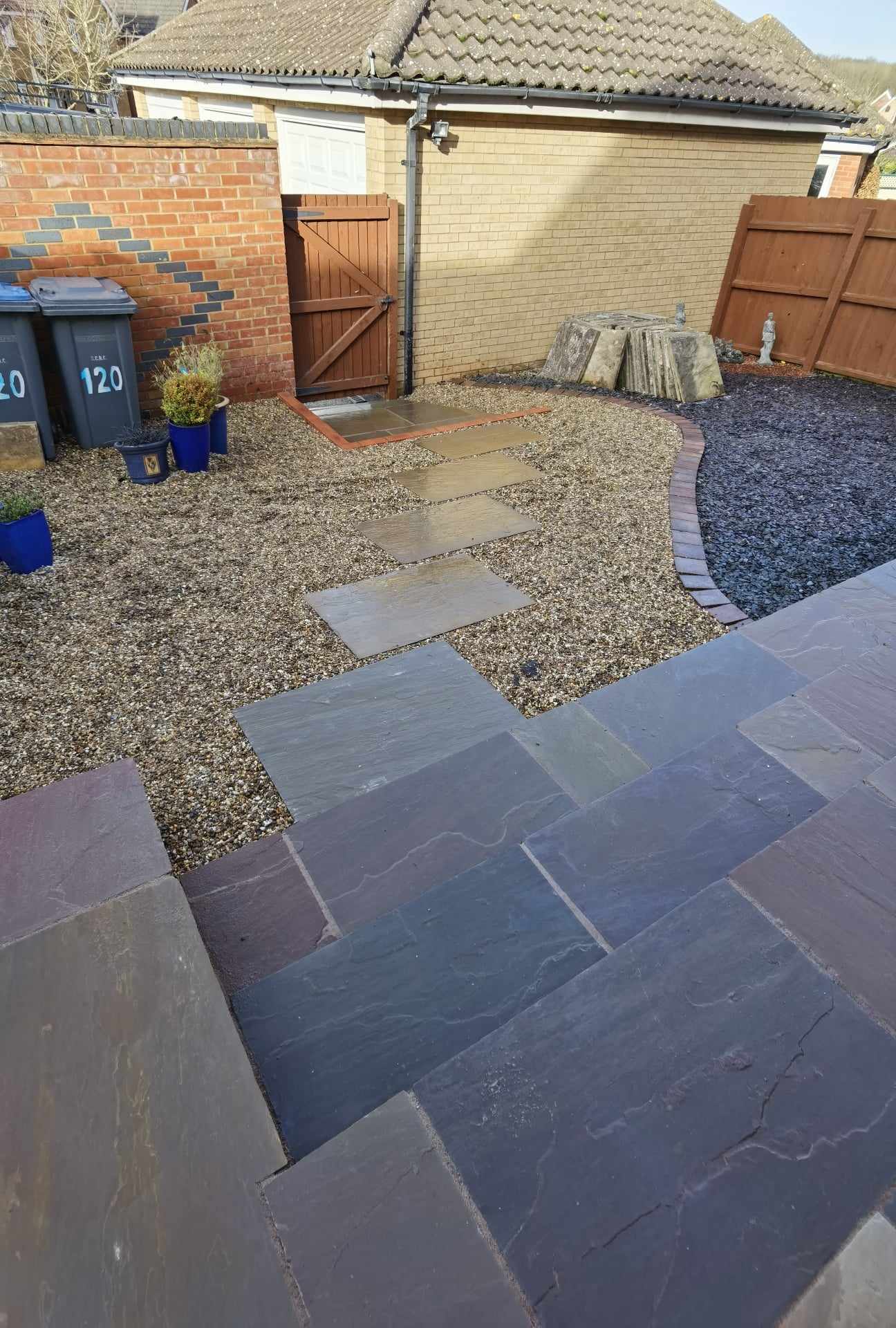 Patio installation Suffolk — Slate stone patio with stepping stones and gravel pathways in residential courtyard