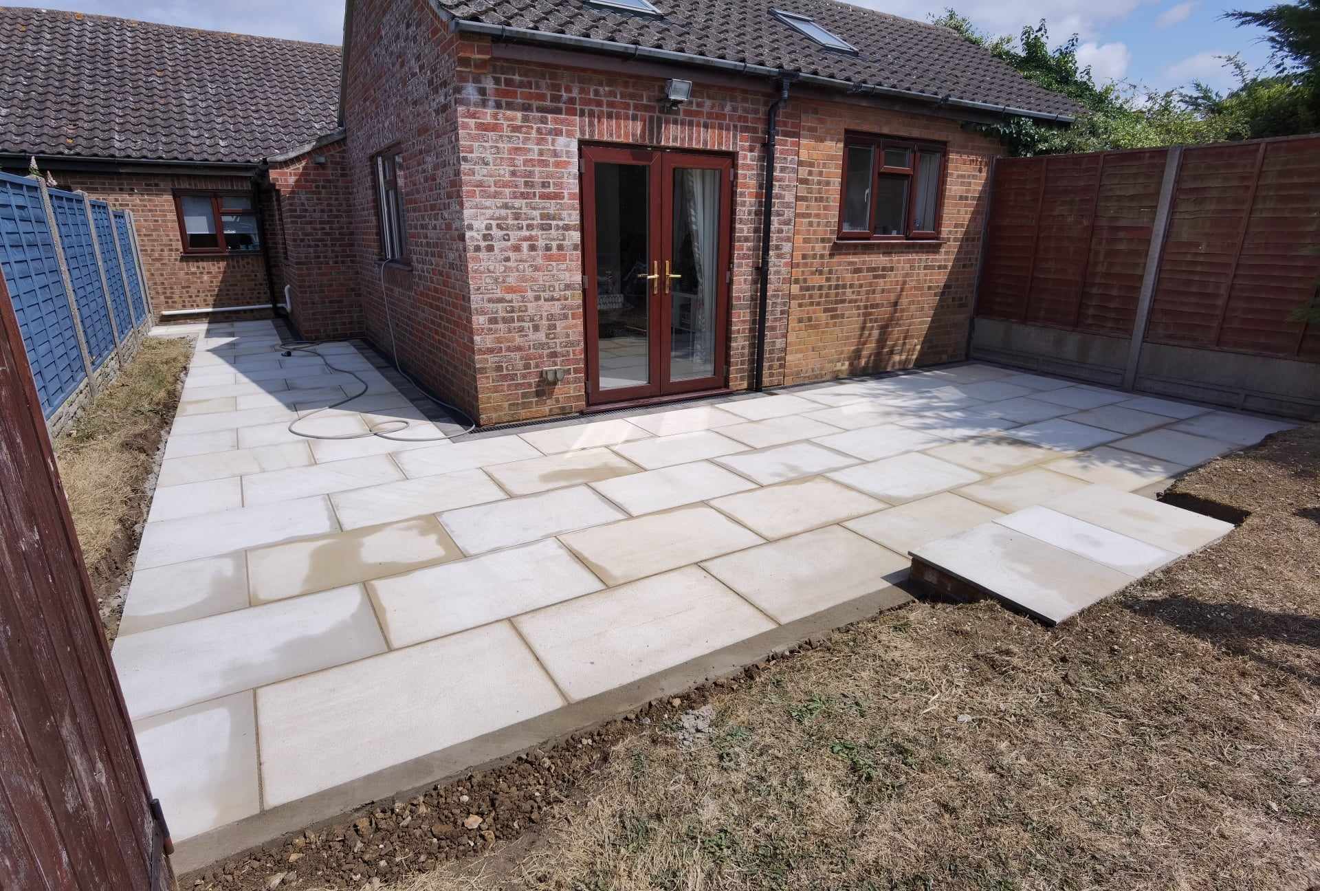 Patio installation Suffolk — Large Indian sandstone patio installation in progress, partially laid