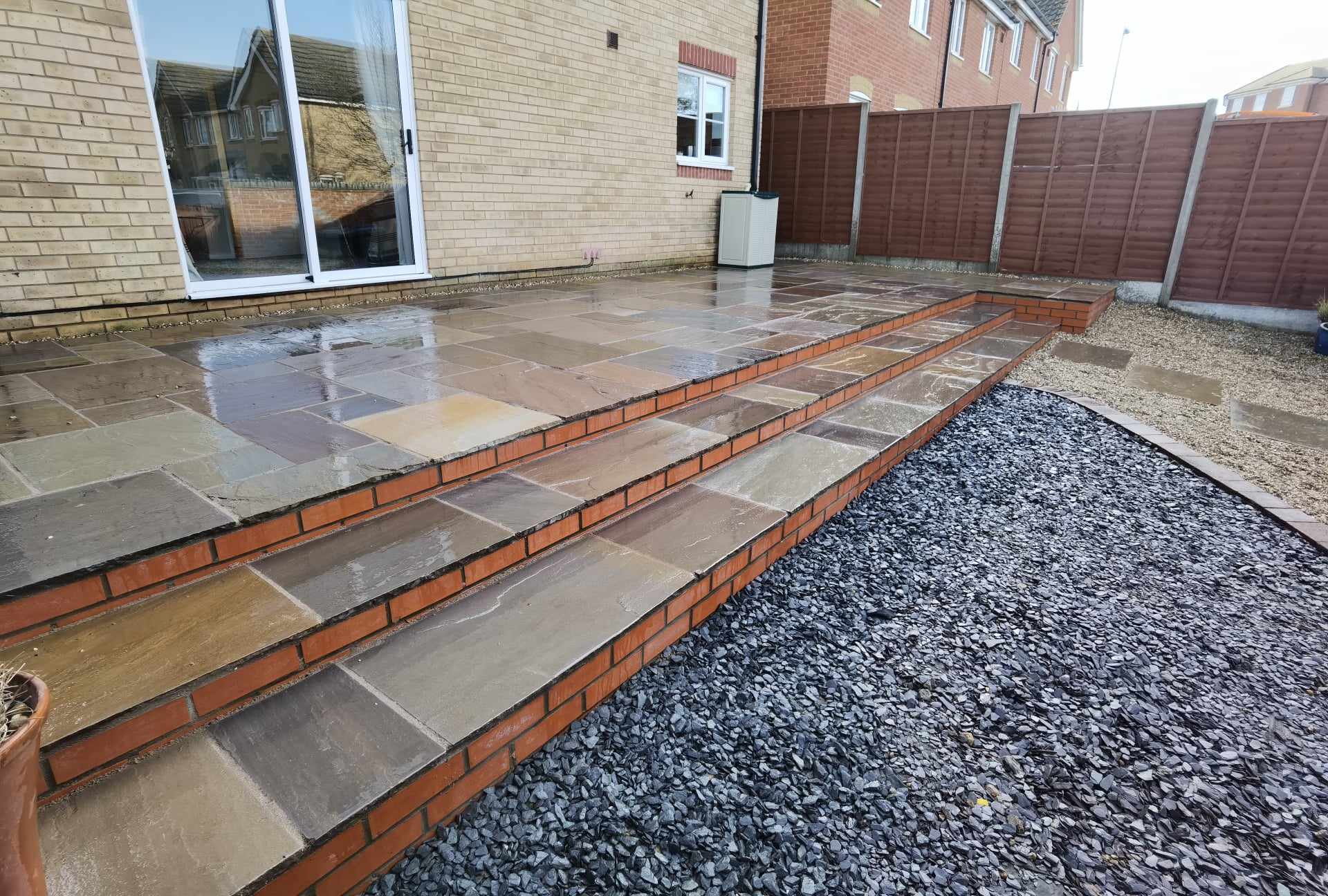 Patio installation Suffolk — Newly installed stone slab patio with brick edging and gravel border