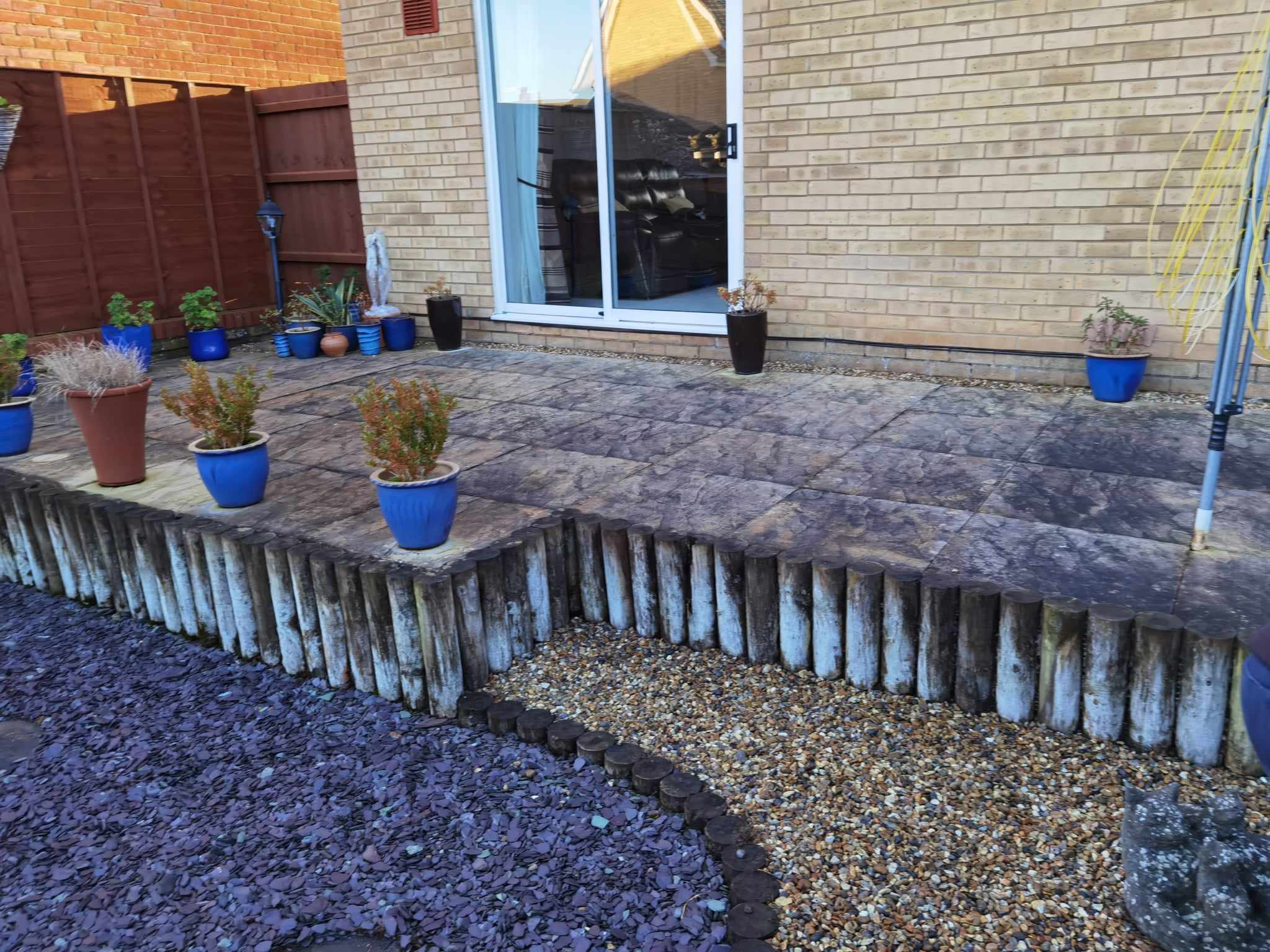 Patio installation Suffolk — Stone slab paved courtyard with decorative potted plants and timber edging