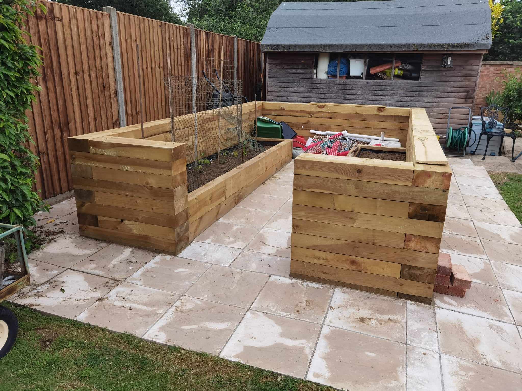 Raised bed garden Suffolk — Two wooden raised garden beds with protective netting on patio area