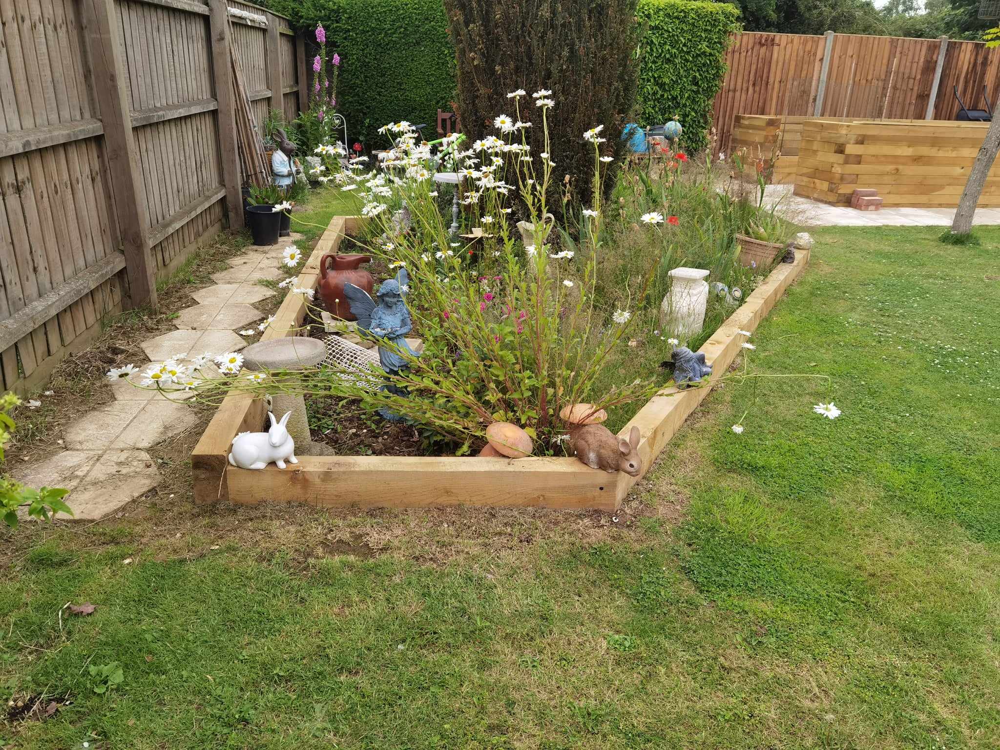 Raised bed garden Suffolk — Wooden raised garden beds with flowering plants and decorative garden ornaments
