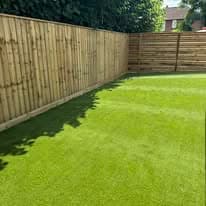 Turfing & lawn Suffolk — Well-maintained real grass lawn with wooden fencing backdrop