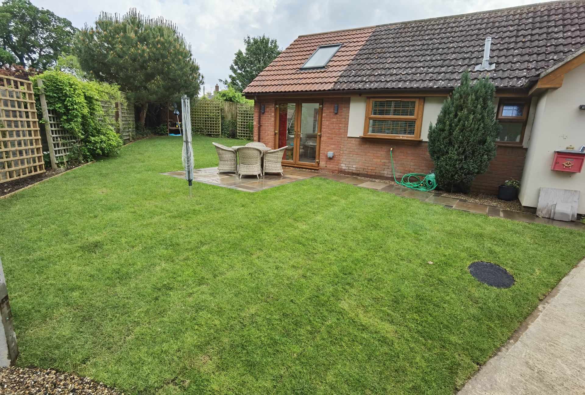 Turfing & lawn Suffolk — Well-maintained real grass lawn with patio seating area and modern bungalow