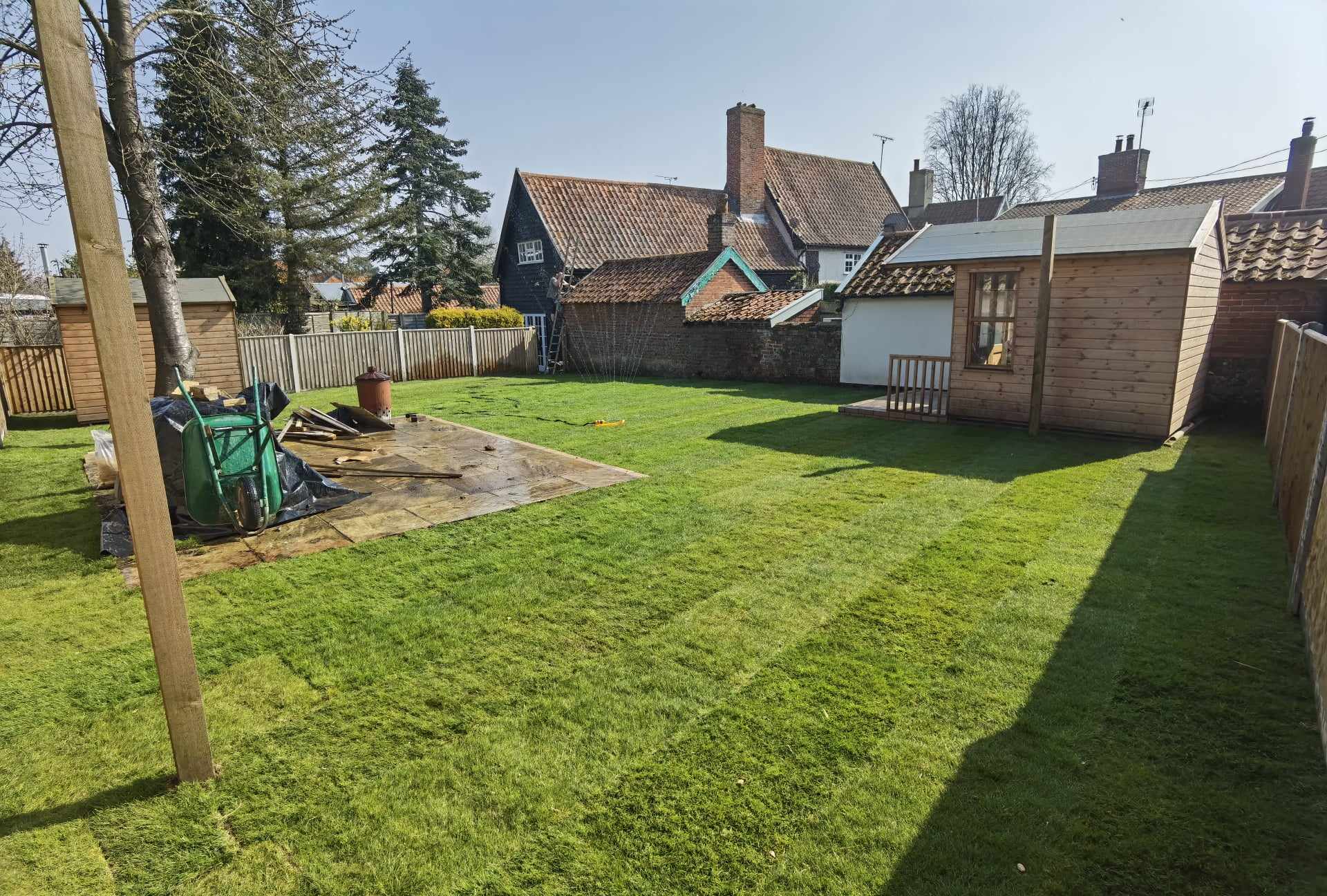Turfing & lawn Suffolk — Well-maintained green grass lawn with garden outbuildings and fencing